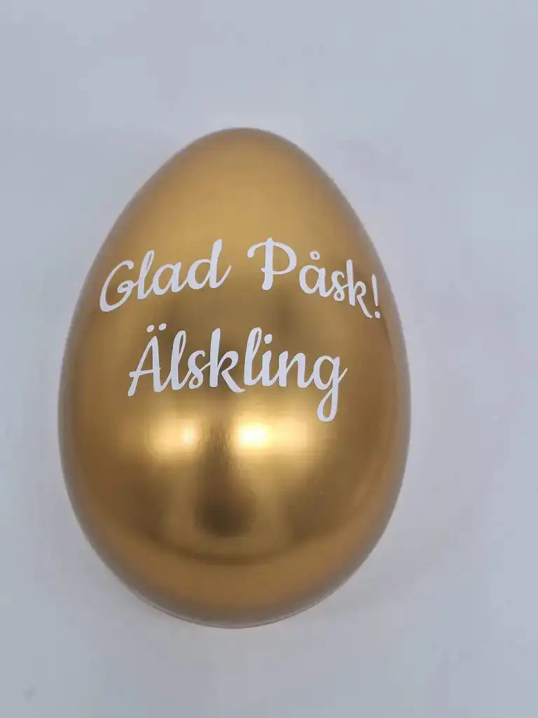 Ett glänsande guldägg med orden Glad Påsk! Älskling skrivet i vitt, vilket betyder Glad Påsk! Älskling.