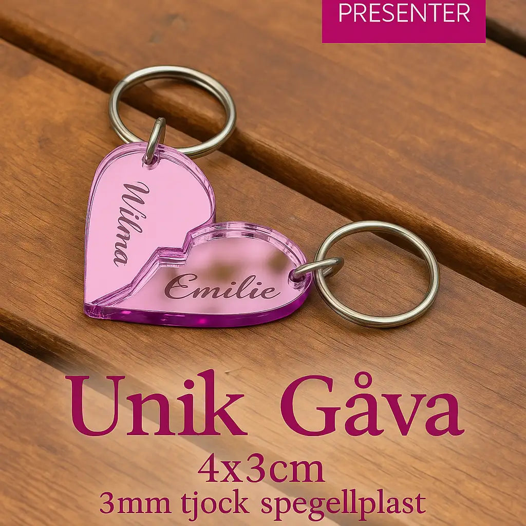 Två rosa "Nyckelring - Halvt hjärta i spegelplast (rosa)" från Express-presenter, med namnen Vilma och Emilie, länkas ihop på träyta. Text: Unik Gåva 4x3cm, 3mm tjock spegelplast.