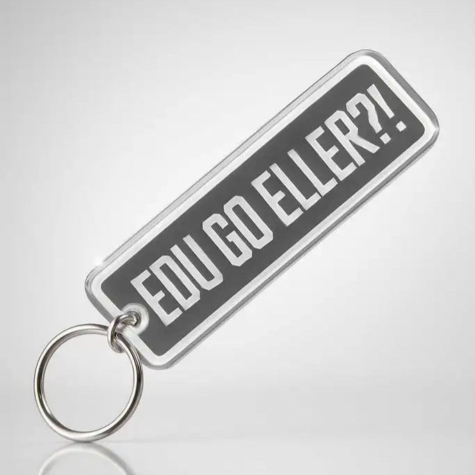 Nyckelringen "Edu go eller" från Express-presenter är en rektangulär nyckelring i akryl med metallring och texten "EDU GO ELLER?!" i fet vit på grå färg. Den är tillverkad av 3 mm plast och kombinerar stil och hållbarhet.