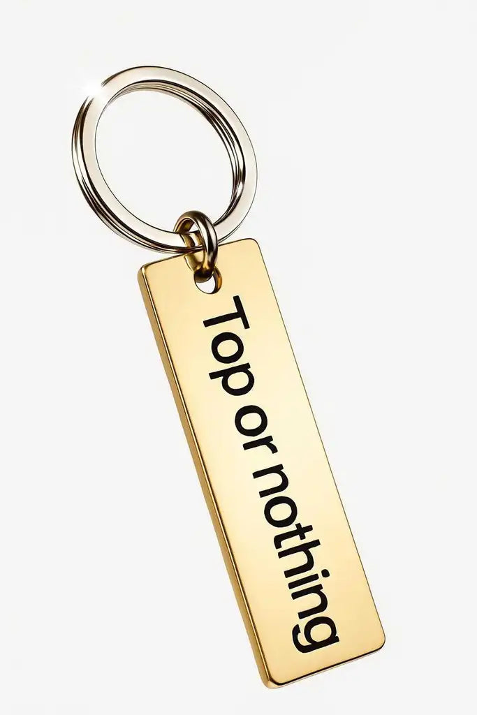 Nyckelring | Topp eller ingenting från Express-presenter: En rektangulär nyckelring i guld med lasermärkt text "Top or nothing" i svarta bokstäver, fäst vid en blank metallnyckelring mot vit bakgrund.