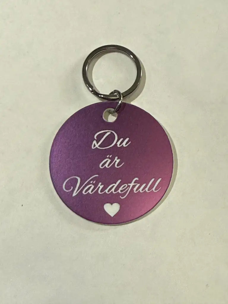 Nyckelring | Du är värdefull (lila) från Express-presenter: Rund, mörklila nyckelring med silverfärgad text "Du är Värdefull" och litet hjärta. Diameter 40 mm.