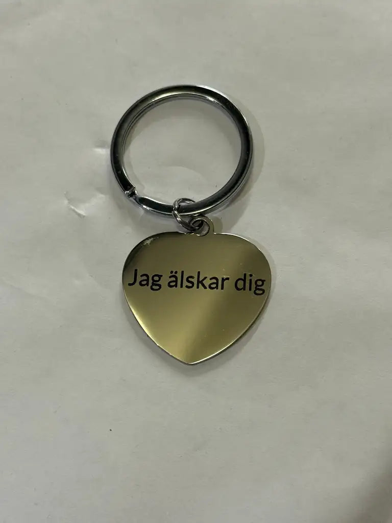 Express-presenter Nyckelring | Jag älskar dig är en silverfärgad hjärtformad nyckelring i rostfritt stål med "Jag älskar dig" lasermarkerat på vit botten.
