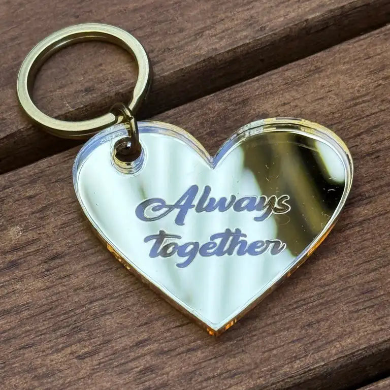 Nyckelringen - Always together by Express-presenter är en guldfärgad, hjärtformad nyckelring i spegelplast (4x3 cm) med texten "Always together" ingraverad på en träyta.