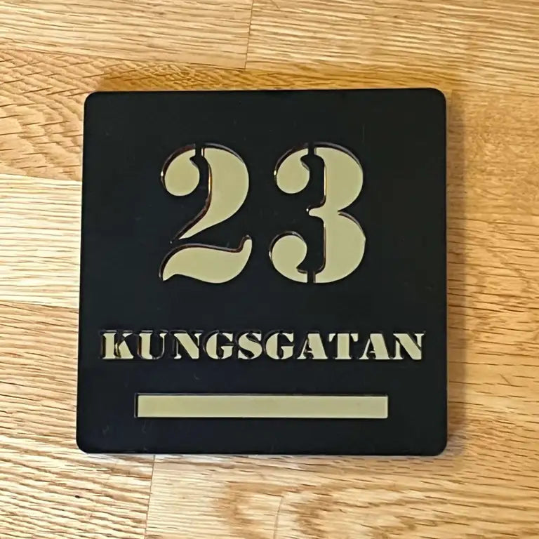 En Snygg Fasadskylt från Express-presenter har svart med guldfärgad text som visar "23 KUNGSGATAN" på trä, vilket framhäver dess exceptionella kvalitet.