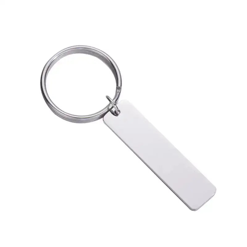 Nyckelring | skriv din text från Express-presenter - en silverfärgad metallnyckelring med tom rektangulär tag, perfekt som personlig nyckelring eller present till pedagog. Visas mot vit bakgrund.