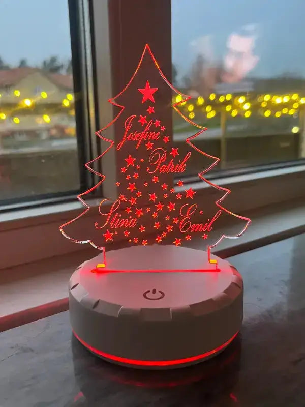 Express-presenters "Julklappstips med familjens namn" är en självlysande julgran i akryl med personlig gravyr och en röd LED-nattlampa, som visar namnen Josefine, Patrik, Stina och Emil på en fönsterbräda med gula lampor utanför.