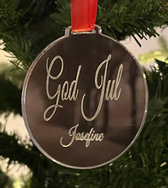 Julgranshänge God Jul från Express-presenter, med "God Jul Josefine" ingraverat, hänger i ett rött band i julgranen.