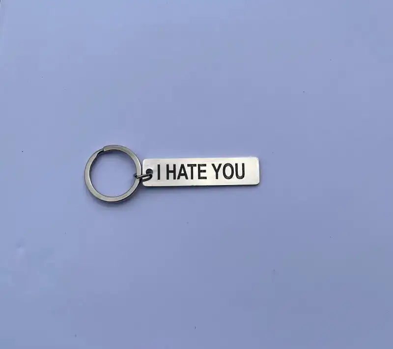 Nyckelringen | I hate you by Express-presenter är en silverfärgad nyckelring med en rektangulär tagg i rostfritt stål, laseretsad med "I HATE YOU" i feta svarta bokstäver mot en ljuslila bakgrund.