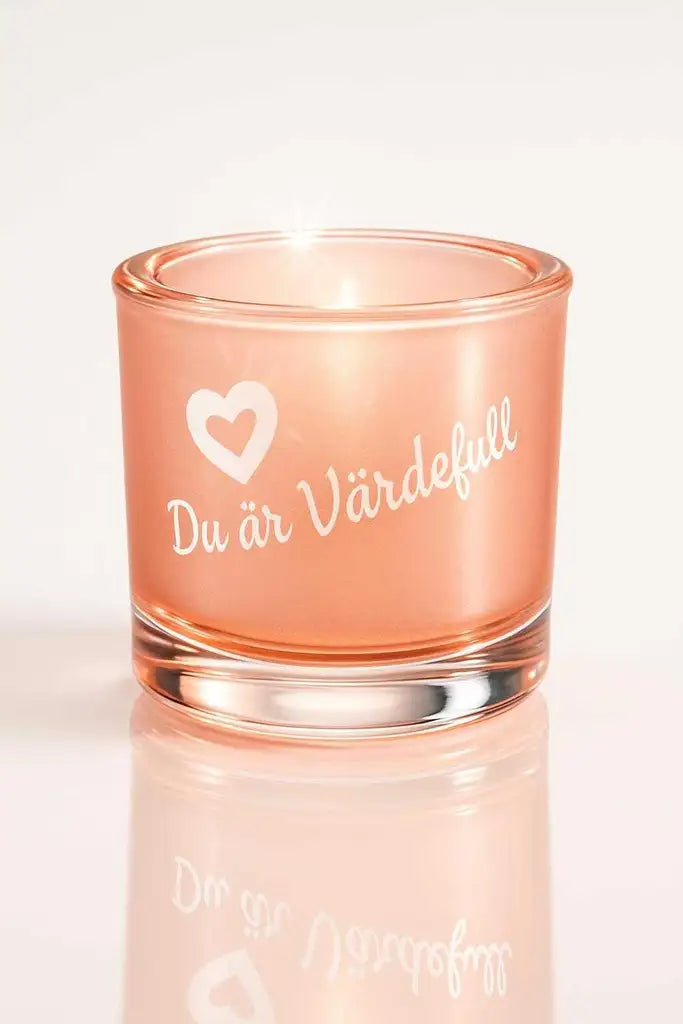 Ljuslyktan Du är Värdefull från Expresspresenter.se är en liten ljuslykta i rosa glas med ett vitt hjärta och texten "Du är värdefull" tryckt på, mot en vit bakgrund.