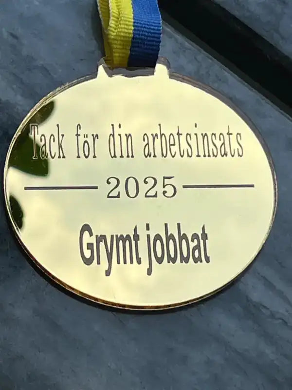 Medalj | Grymt jobbat från Express-presenter är en guldmedalj med ett blågult sverigeband, ett blågult band och svensk gravyr: "Tack för din arbetsinsats 2025 Grymt jobbat." Tillverkad av slitstark spegelplast.