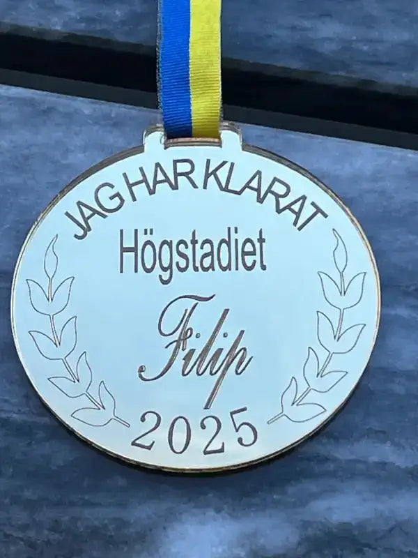 Medalj | Högstadiet by Express-presenter är en spegelplast guldmedalj med blågult band, graverad med "JAG HAR KLARAT Högstadiet Filip 2025" och lagerkvistar - perfekt för att fira högstadiets prestationer.