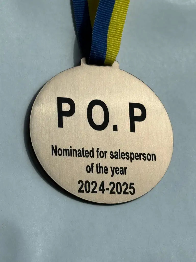 Medaljen Nominerad för bästa från Express-presenter är en guldmedalj med blågult band och graverad akryl "P.O.P Nominerad till årets säljare 2024-2025", perfekt för nästa kickoff, mot en ljus bakgrund.