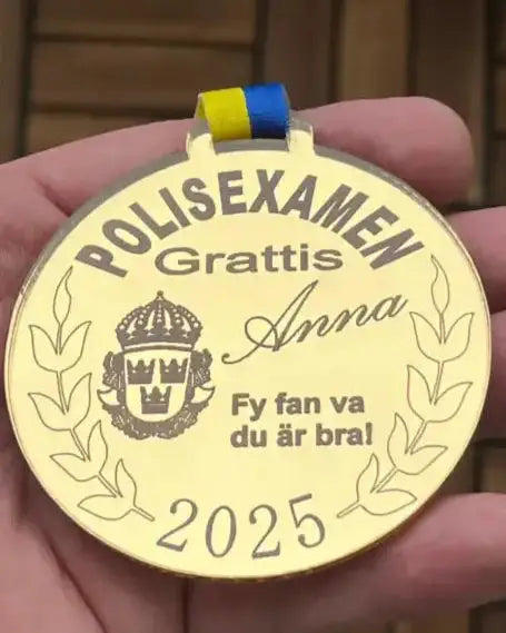 Express-presenters Medalj | Polisexamen med blå/gul rosett, texten "Polisexamen Grattis Anna, Fy fan va du är bra! 2025", svensk krona och lagerkvistar hålls i en hand.