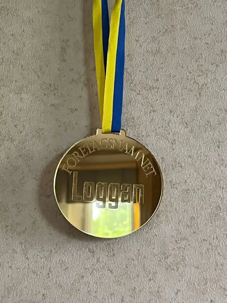 En guldmedalj med "Loggan" och ditt företagsnamn, från Express-presenter, hänger på ett blågult band - en elegant specialprodukt, Medalj | Företagsevent, perfekt för företagsevent.