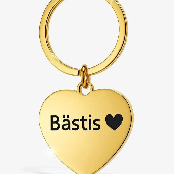 Express-presenters "Nyckelring | Bästis med hjärta" består av en nyckelring i guld med ett hjärtformat hänge i rostfritt stål, lasergraverat med "Bästis" och ett svart hjärta, mot en vit bakgrund.