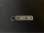 Nyckelringen | I hate you by Express-presenter är en rektangulär nyckelring i akryl med metallring och en genomskinlig tagg med texten "I HATE YOU" i feta vita bokstäver på en svart yta.