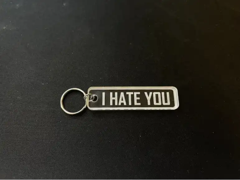 Nyckelringen | I hate you by Express-presenter är en rektangulär nyckelring i akryl med metallring och en genomskinlig tagg med texten "I HATE YOU" i feta vita bokstäver på en svart yta.