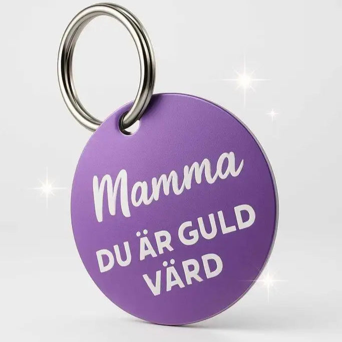 Nyckelring Mamma du är guld värd (Lila) från Express-presenter: Rund mörklila plast med graverad bricka, vit text "Mamma DU ÄR GULD VÄRD", metallring. Visas mot ljus bakgrund med gnistrande effekt.