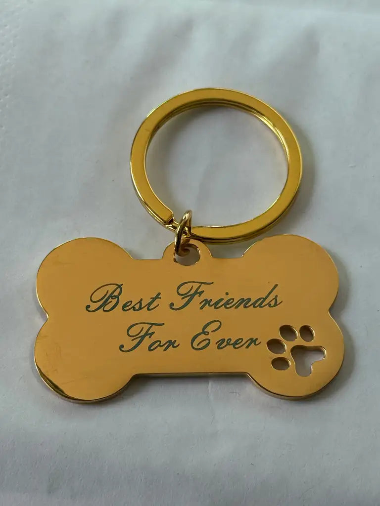 Express-presenter Nyckelring | Hundben Best friends for ever är en guldig nyckelring med lasergraverad text och ett litet tassavtryck på vit yta.