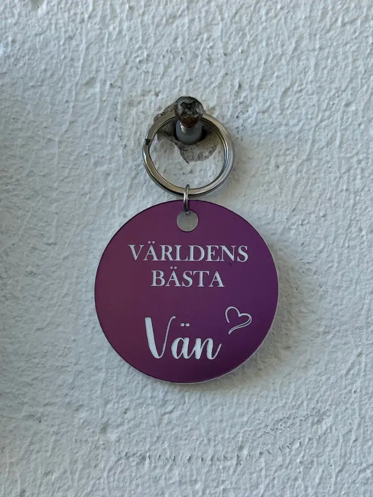 En lila, graverad plastnyckelring från Express-presenter med svensk text: "Världens bästa vän" och ett hjärta - en fin present till din bästa vän.