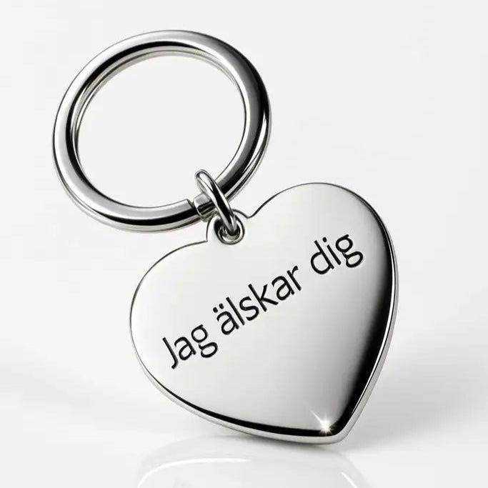 En silverfärgad hjärtformad nyckelring i rostfritt stål från Express-presenter med texten "Jag älskar dig", fotograferad mot vit bakgrund. Produktnamn: Nyckelring | Jag älskar dig.