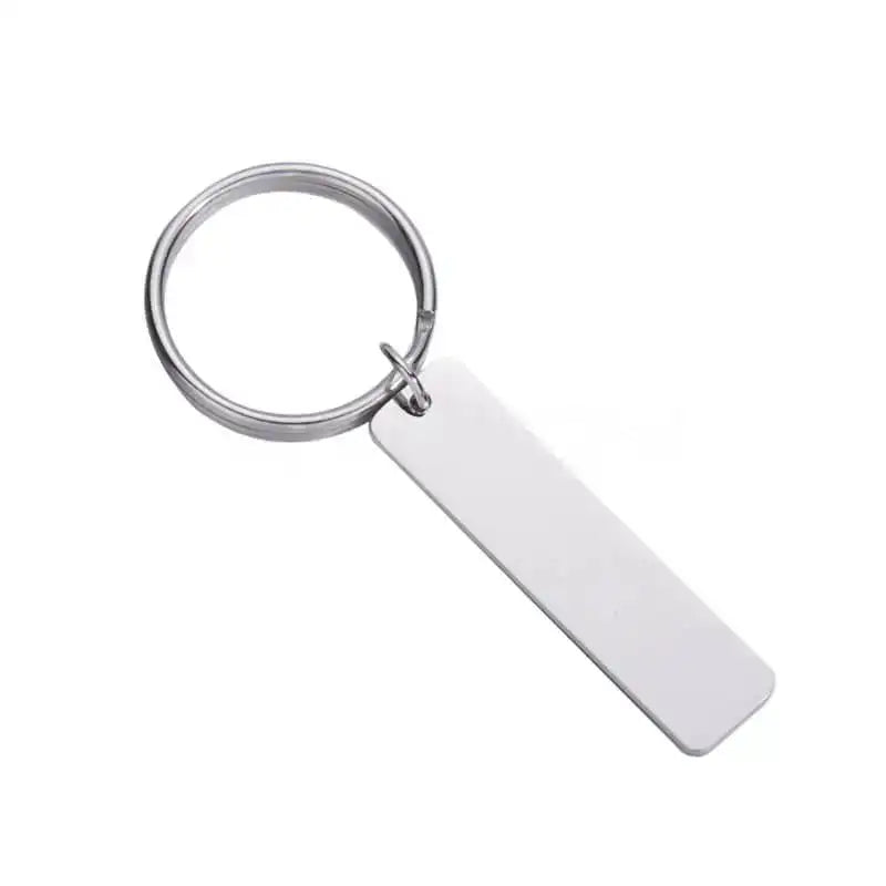 Nyckelring | Take Care by Express-presenter är en silverfärgad nyckelring med en slät rektangulär tagg (12 x 50 mm, rostfritt stål smycke), mot vit bakgrund.