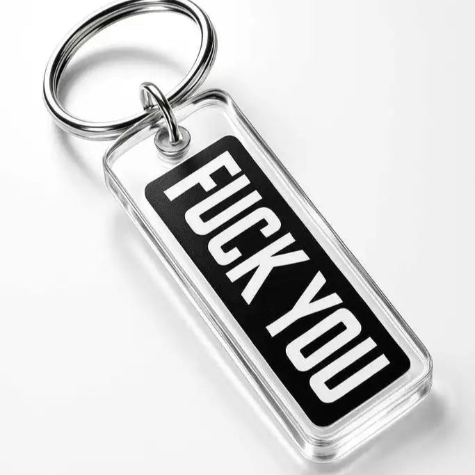 En rektangulär akrylnyckelring från Express-presenter med metallring, svart etikett och vit text "FUCK YOU", placerad på vit yta. Produkten är Nyckelring | Fuck you och har graverad baksida för extra detalj.
